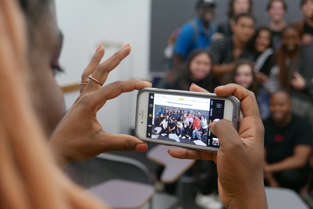 Student taking a group photo with her phone.